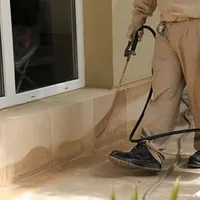 General pest control technician spraying exterior perimeter around a home in Peoria, IL